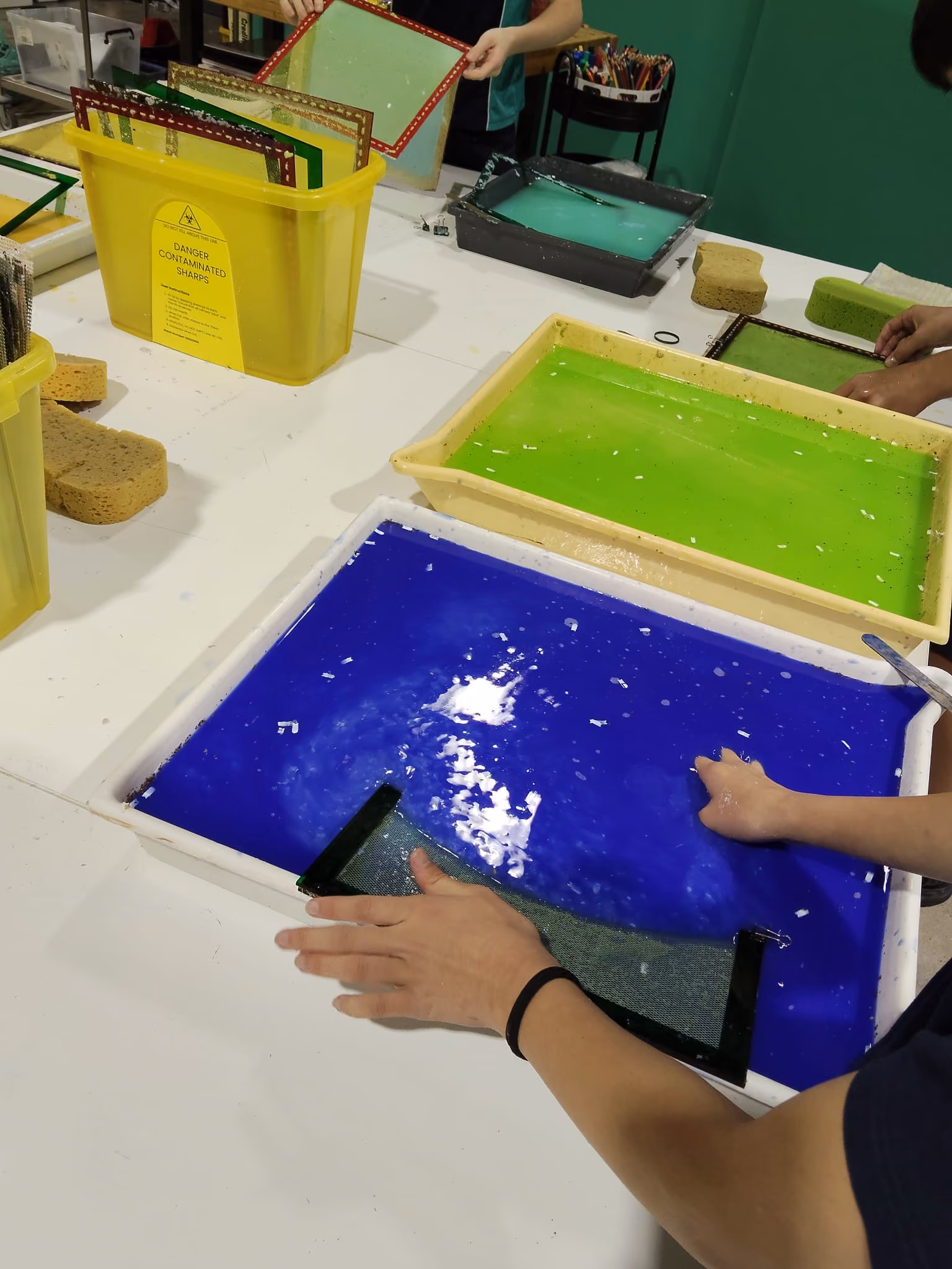 Person painting a blue mesh-shaped object resembling a manta ray with a blue brush and paint.